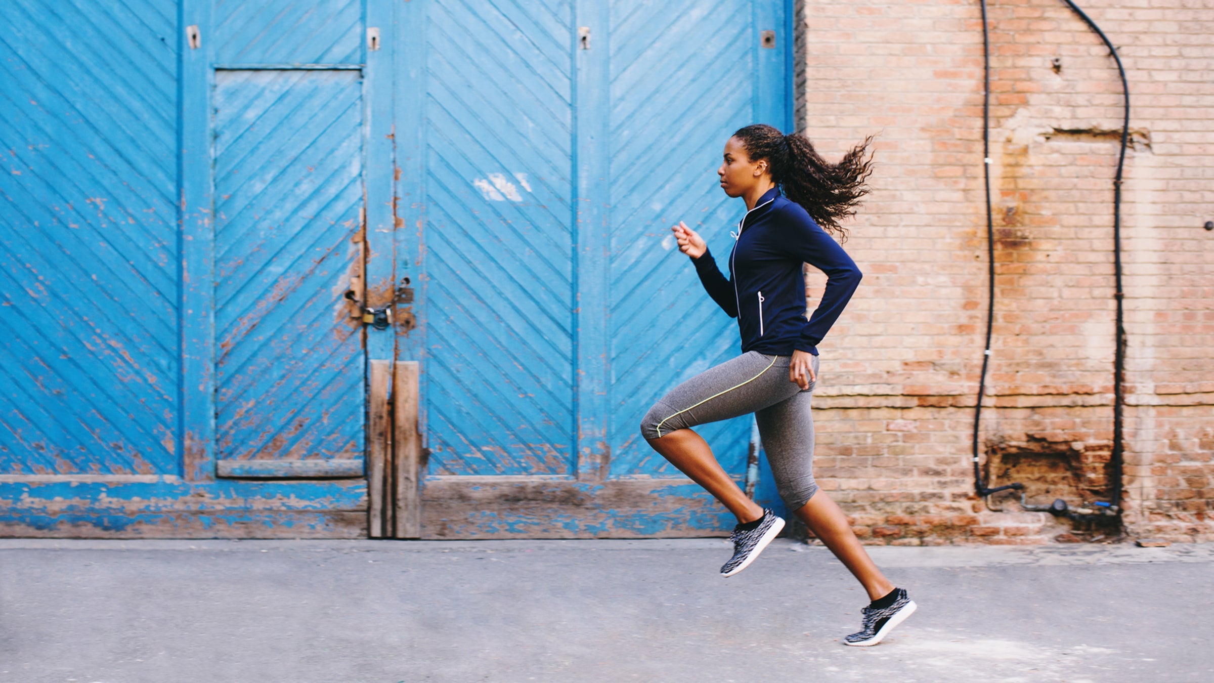 Side View Of An African American Woman Running On The Street.