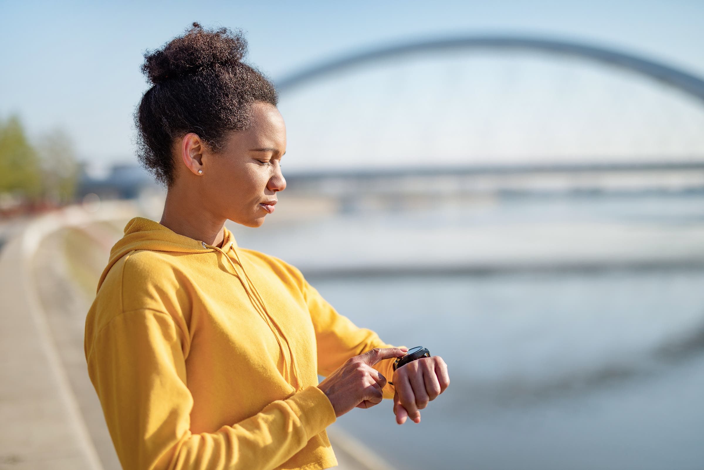 Mid adult African American woman using touch screen smart watch to check why her heart rate is high on an easy run