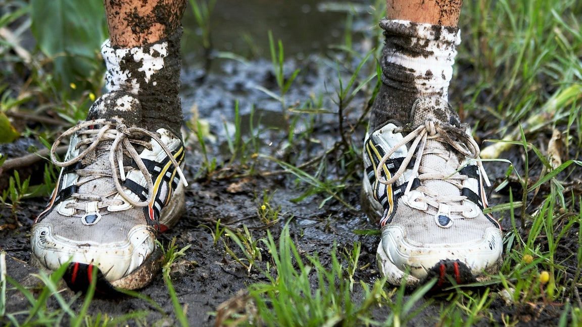 Man standing in dirty running shoe trainers in mud.