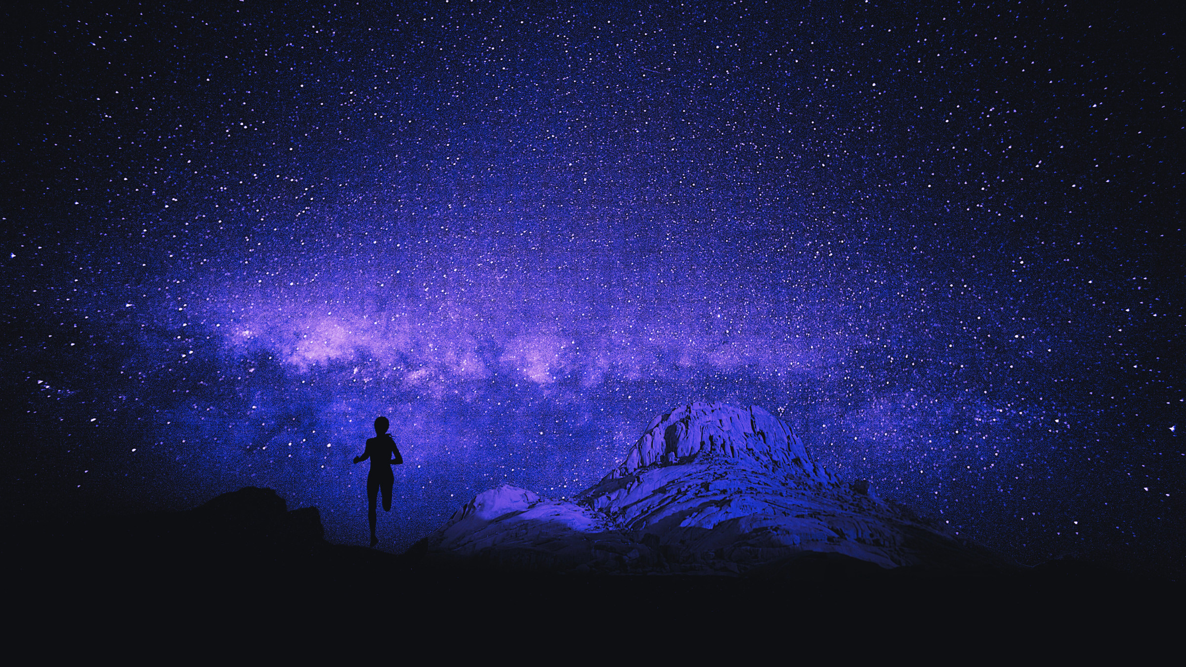 A woman night runs under a starry sky.