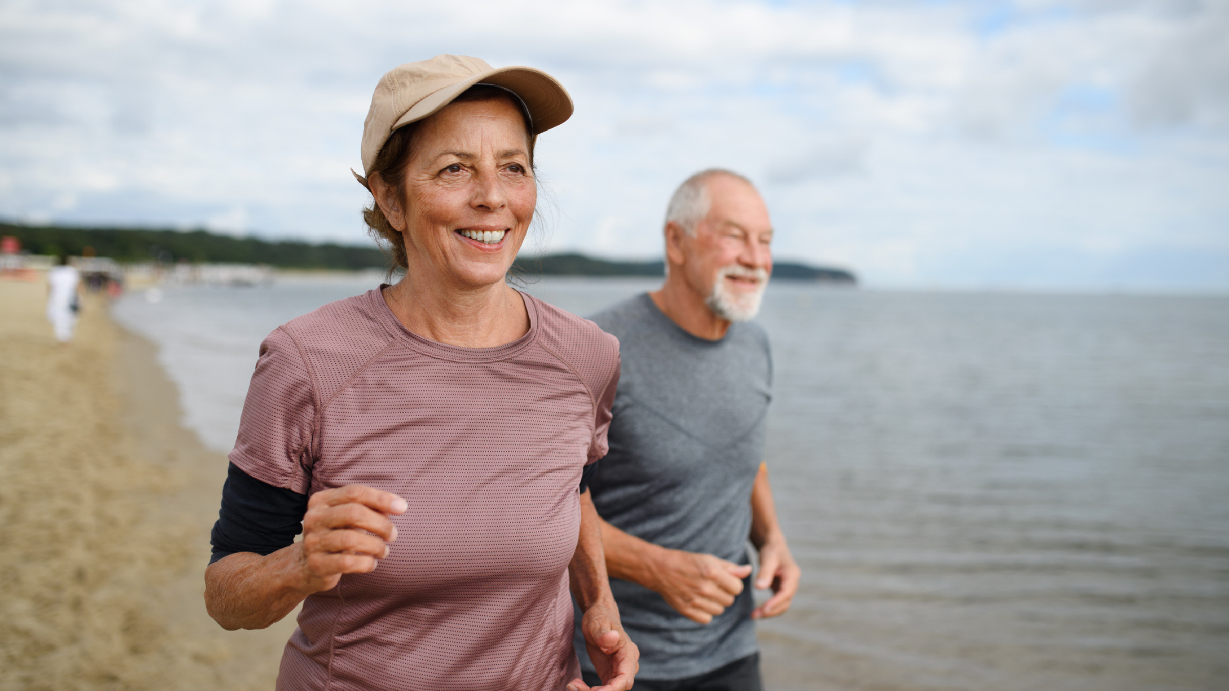an older couple running on the beach
