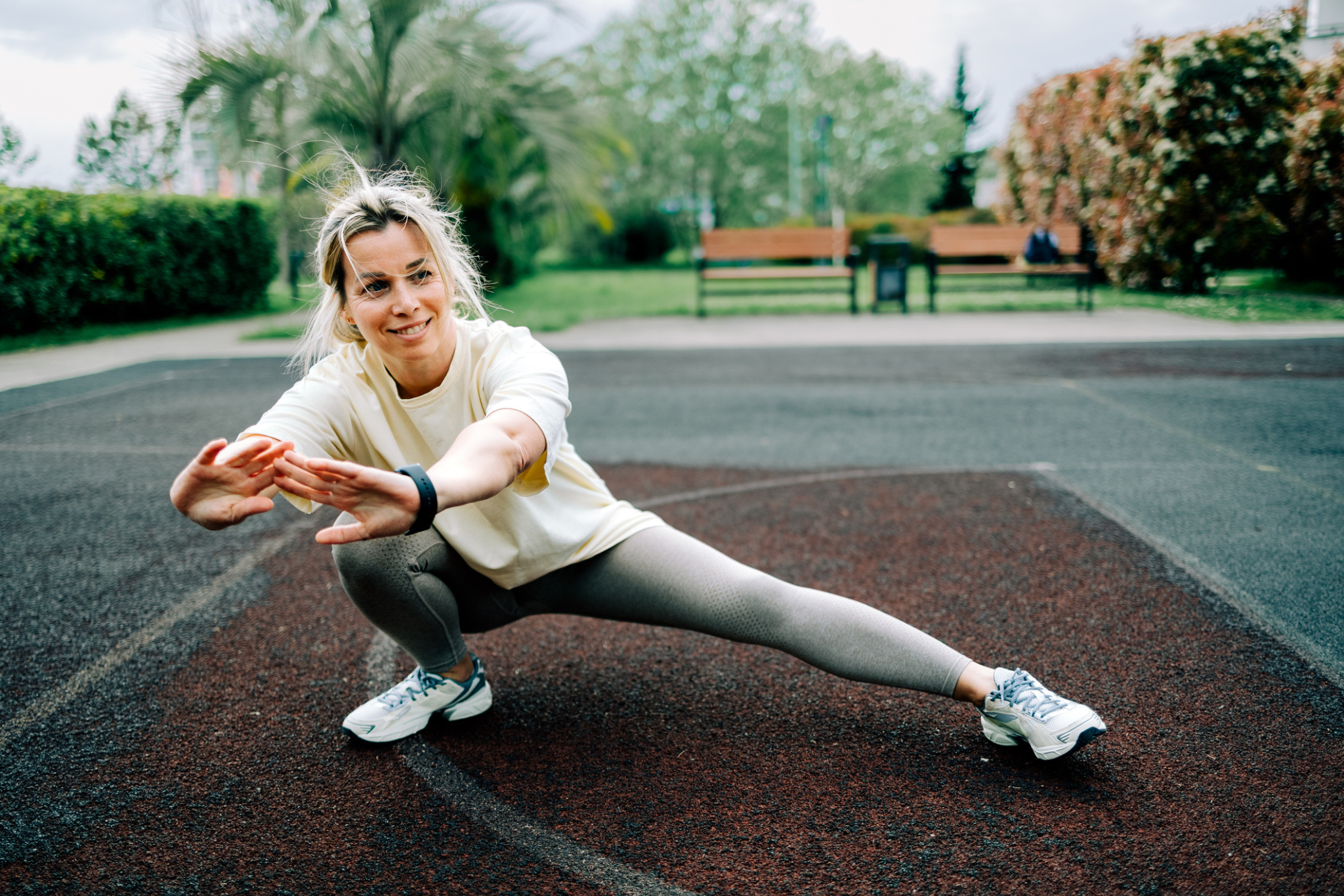 a woman stretches in a lateral lunge in a city park
